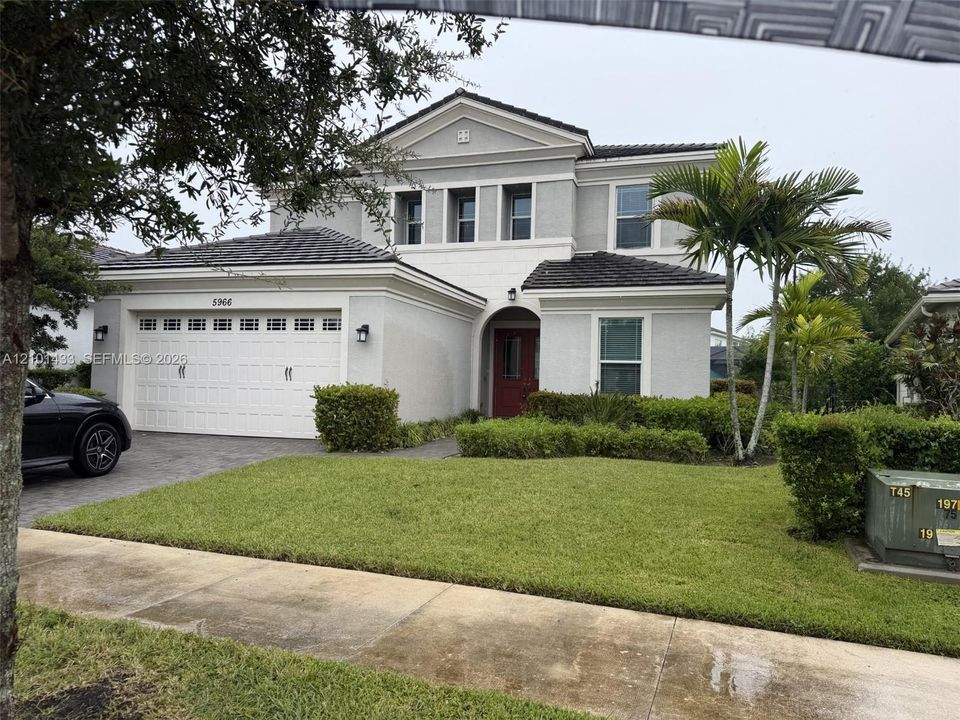 Two-story exterior with a red entry door, white garage door, and a tiled roof