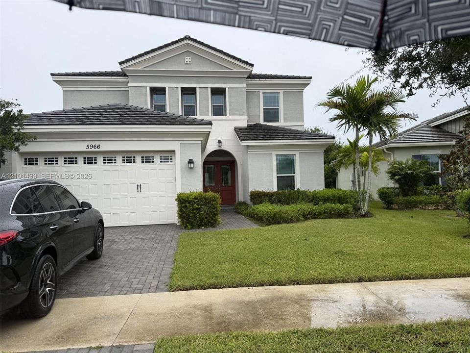 Two-story residence featuring a concrete tile roof, a multi-paneled white garage door, and a paver driveway