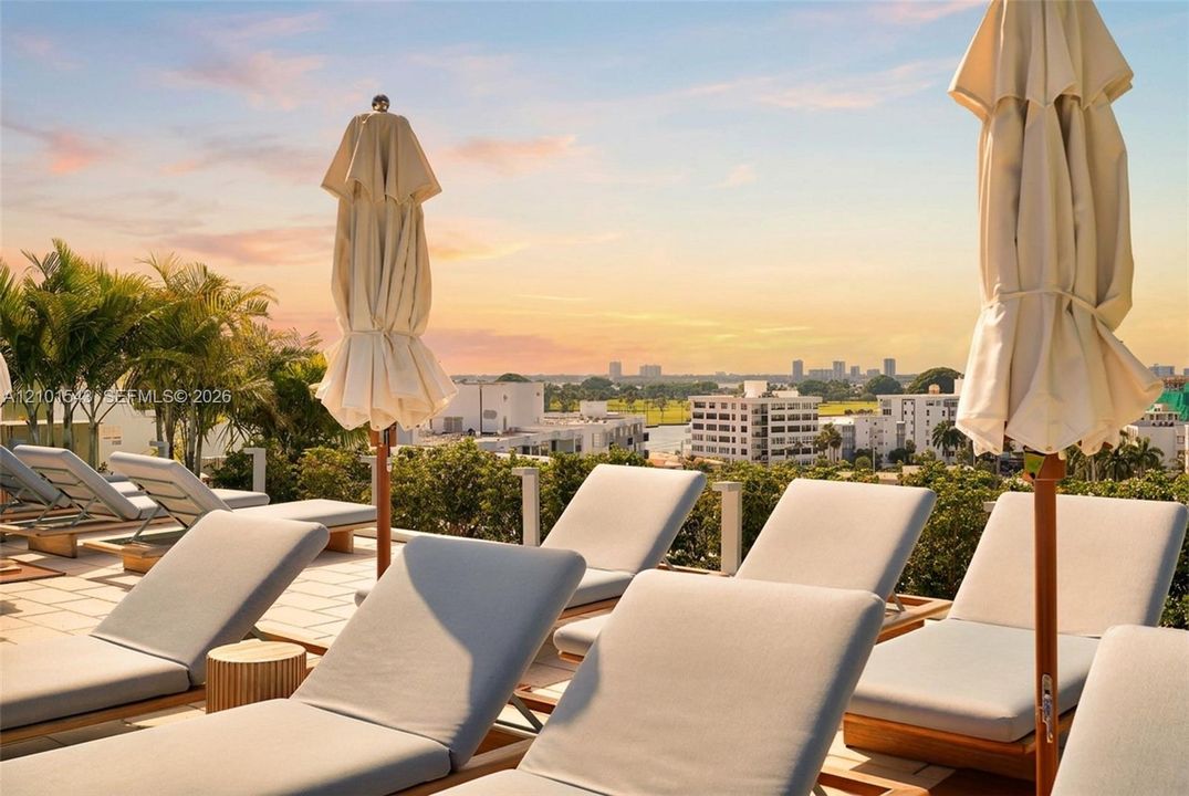 Rooftop terrace featuring light-toned tile flooring, lush perimeter landscaping, and a panoramic skyline backdrop