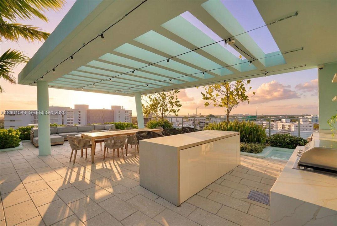Rooftop terrace featuring a structural pergola, stone-paver flooring, built-in kitchen island, and integrated grilling station