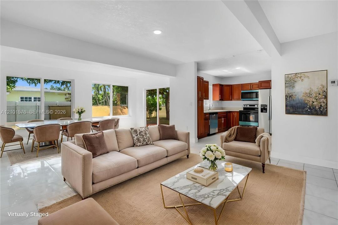 Open-concept interior featuring large-format tile flooring, recessed lighting, and kitchen cabinetry with a wood finish