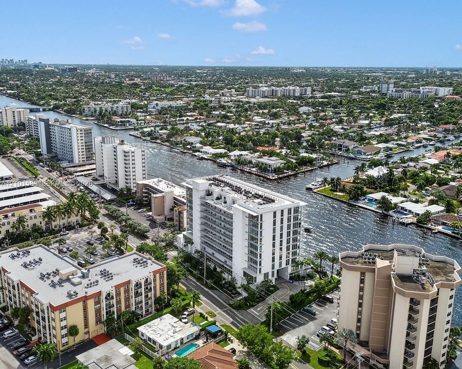 Aerial perspective of a high-rise residential structure positioned along a deep-water canal, featuring expansive balconies, concrete building construction, and proximity to regional waterways