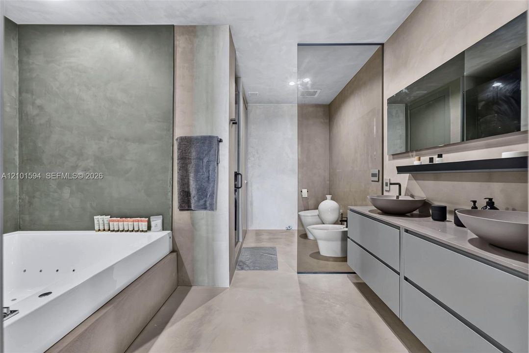 Primary bathroom with oversized spa tub, glass-enclosed shower and dual-sink vanity.