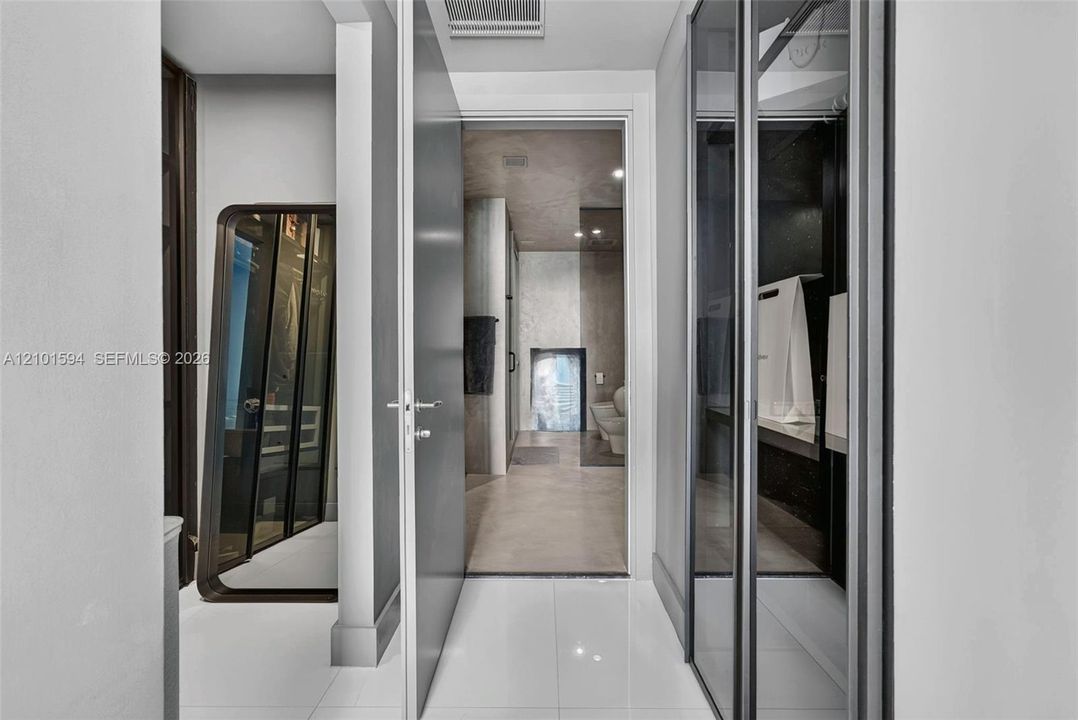 Primary suite hall with Sangiacomo glass-enclosed closets, leading to the primary bath.