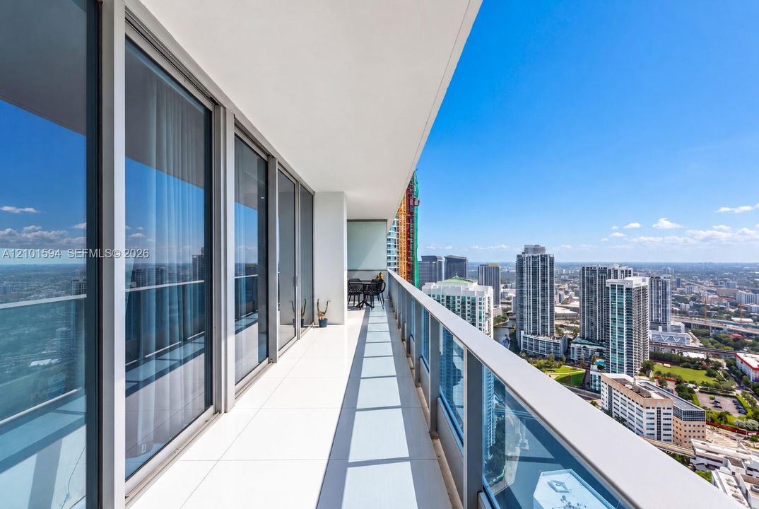 Long private balcony with glass railing and expansive skyline views.