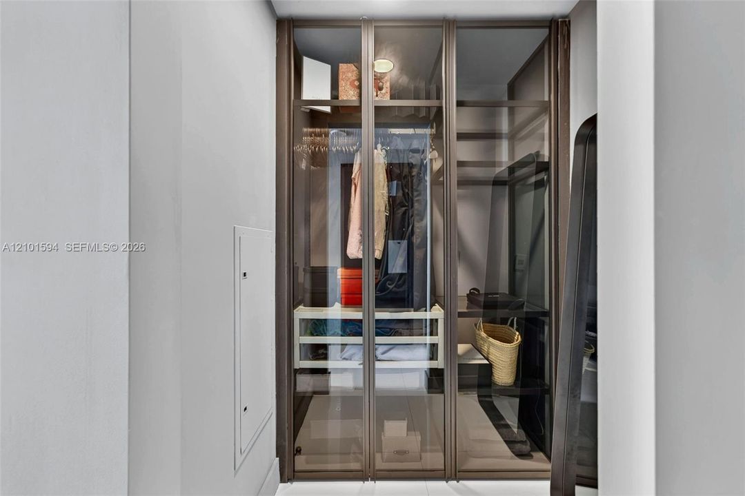Sangiacomo glass-enclosed walk-in closet with extensive built-in shelving and hanging space.