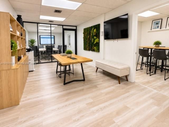 Wood-finish flooring, built-in light wood cabinetry, ceiling-mounted recessed lighting, and a black-framed glass wall partition