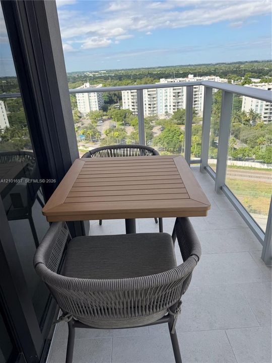 Private balcony with tile flooring and a glass-paneled metal railing