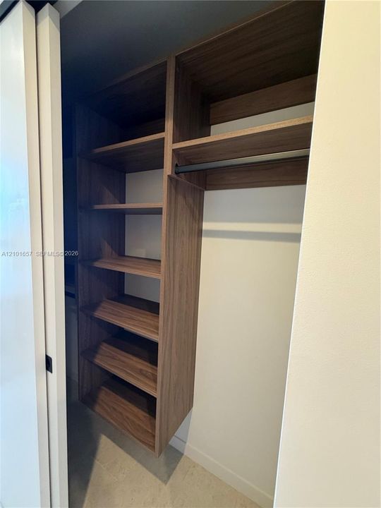 Custom built-in storage unit featuring wood-finish shelving, an integrated hanging rod, and a space-saving sliding door