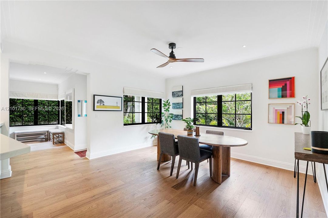 Dining area featuring wood-finish flooring, multi-pane windows with black frames, recessed ceiling lighting, and a three-blade ceiling fan