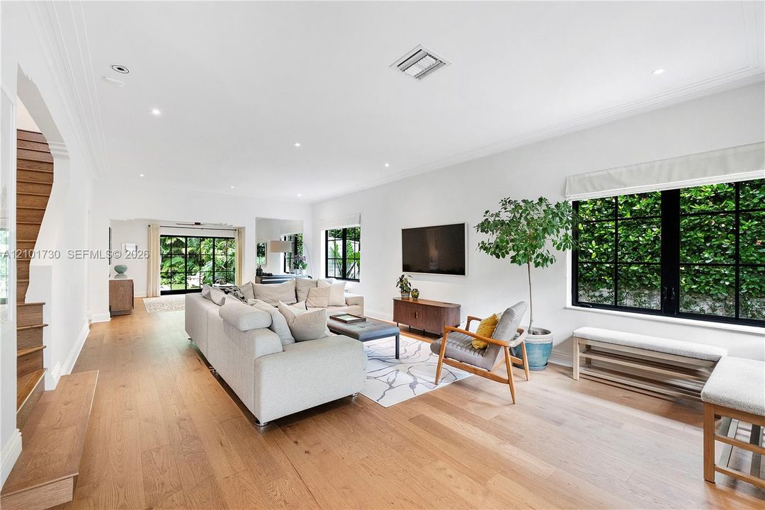 Living area featuring wood-finish flooring, recessed lighting, crown molding, and large windows with black mullions