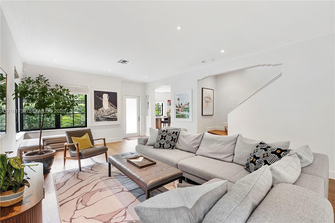 Living area featuring wood-finish flooring, recessed lighting, crown molding, and black-trimmed multi-pane windows