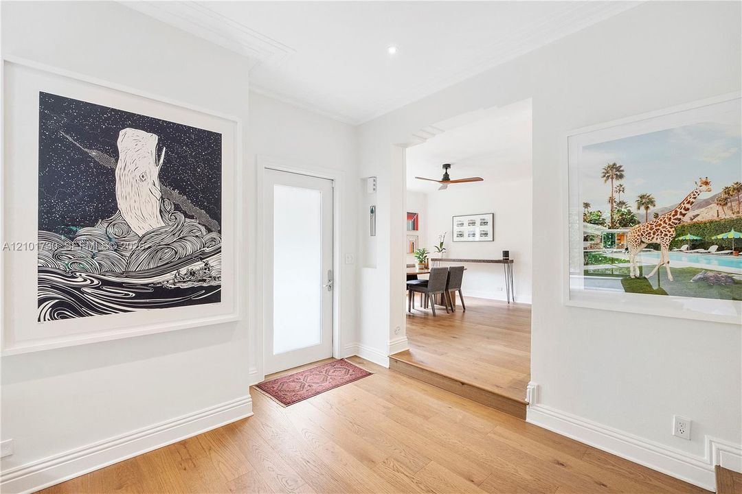 Foyer featuring wood-finish flooring, a recessed entryway with a frosted-glass door, and crown molding