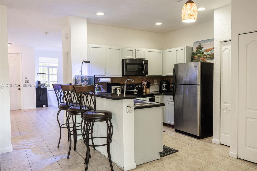 Kitchen featuring white cabinetry, black countertops, stainless steel appliances, and recessed lighting