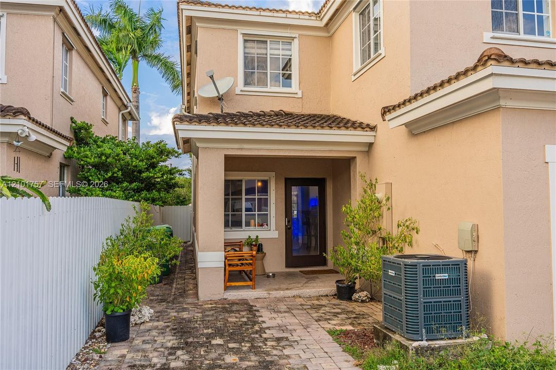 Stucco exterior with a covered entry, tile roof, and white-framed windows