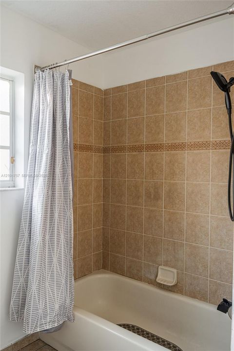 Tiled shower surround with decorative accent band and white tub