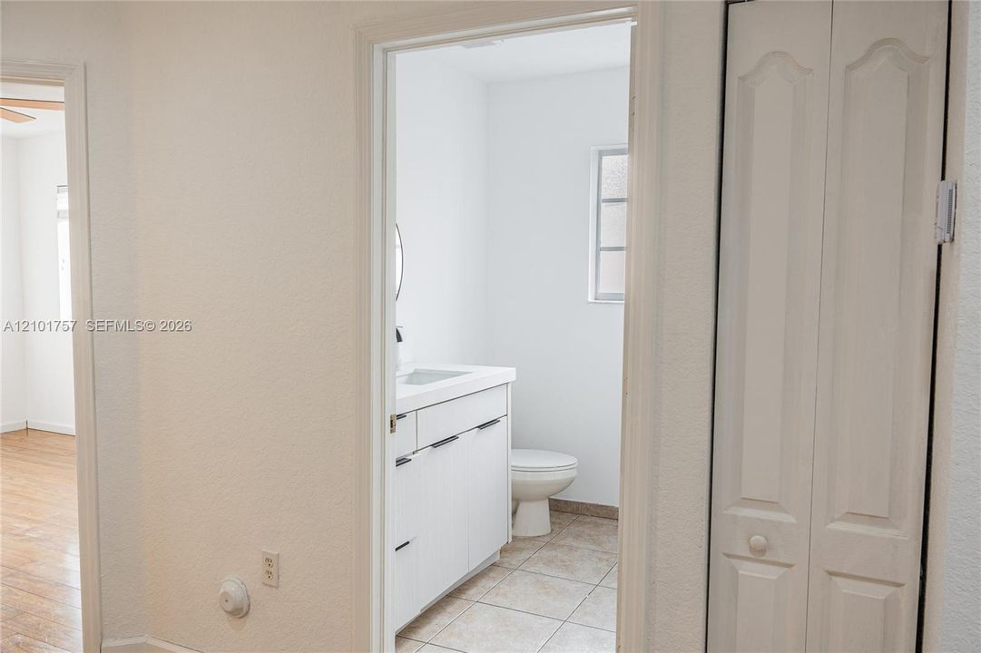 Bathroom with a white vanity and integrated sink, round mirror, and tile flooring