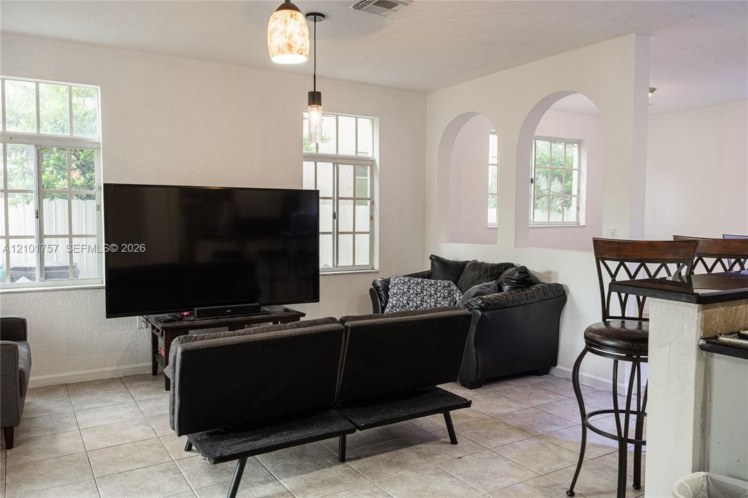 Tiled flooring, multiple windows, double arched wall cut-outs, and pendant lighting