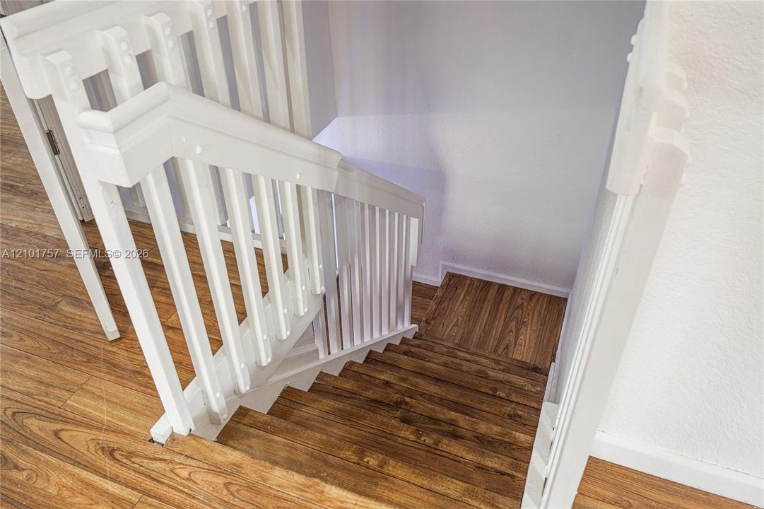 Staircase featuring wood-finish treads and risers, white painted balusters, and a white painted handrail