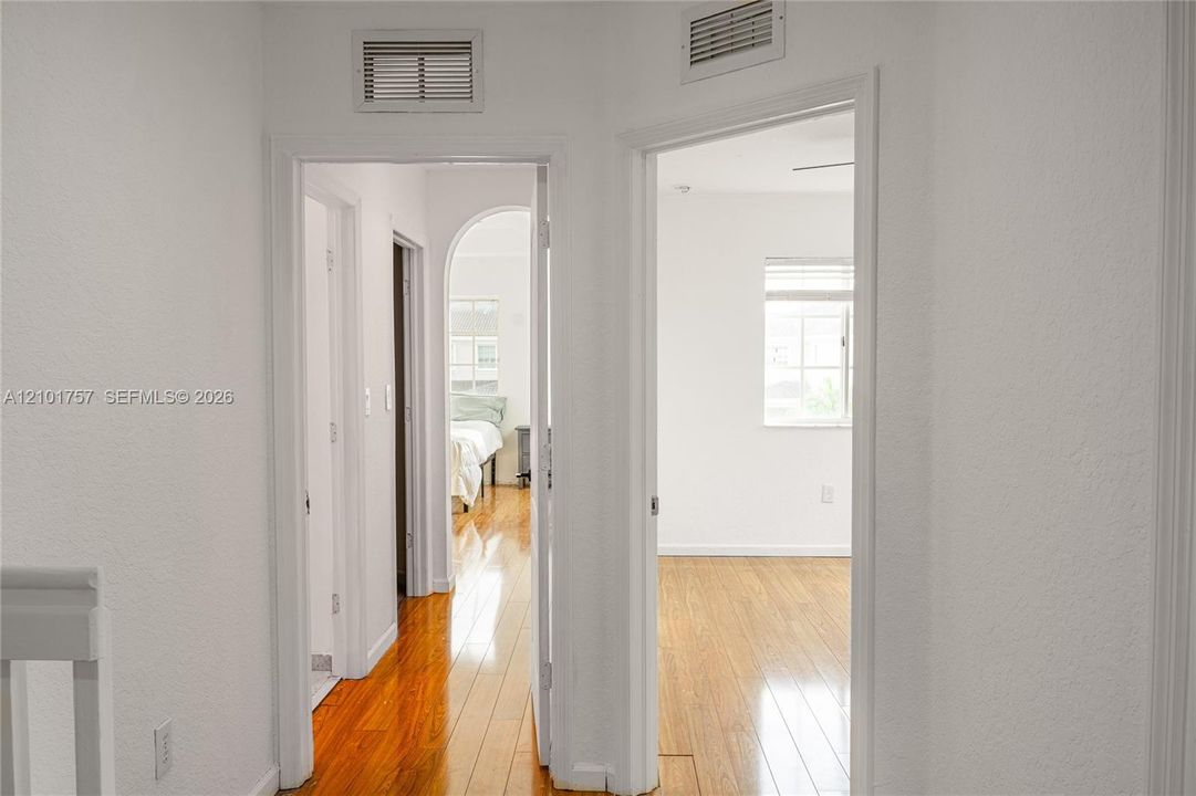 Hallway with wood-finish flooring, white walls, and white trim