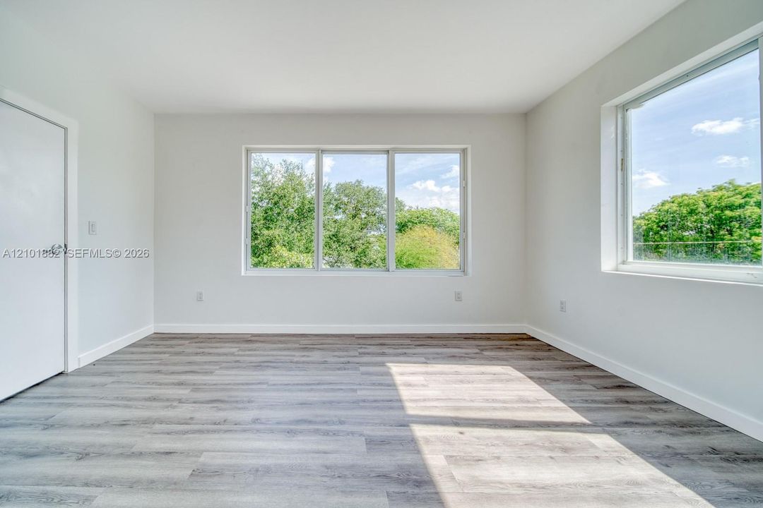 Interior space featuring neutral wall paint, wood-finish flooring, and multiple windows providing natural lighting