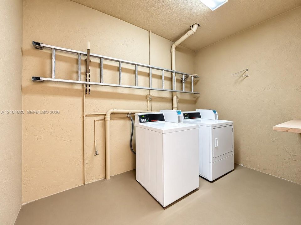 Utility space featuring painted concrete walls, smooth-finish flooring, a ceiling-mounted light fixture, and an integrated wall-mounted equipment rack