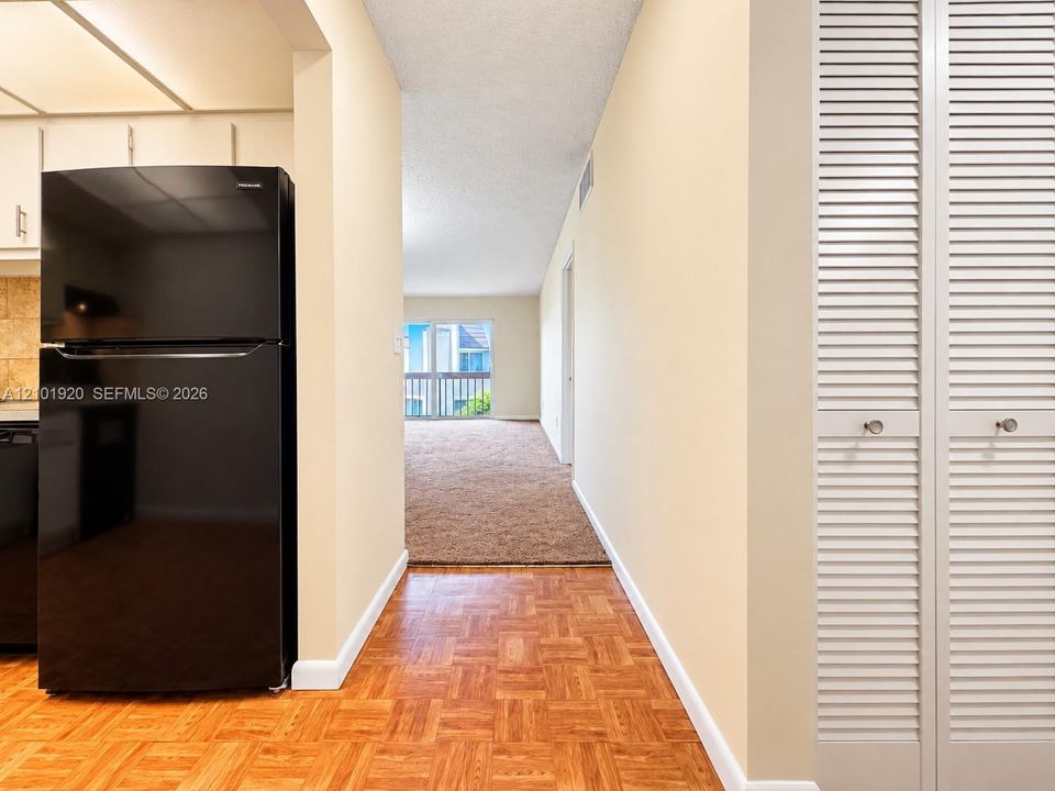 Parquet wood flooring, black top-mount refrigerator, and white louvered-style closet doors