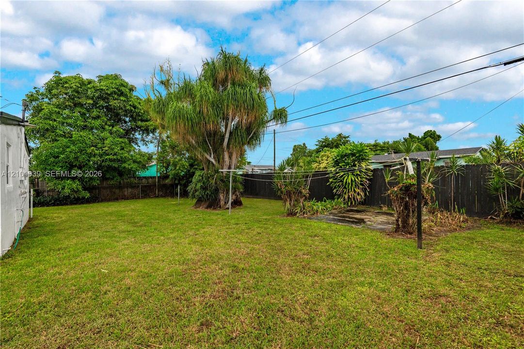 Expansive backyard featuring a level lawn, mature specimen trees, and perimeter privacy fencing