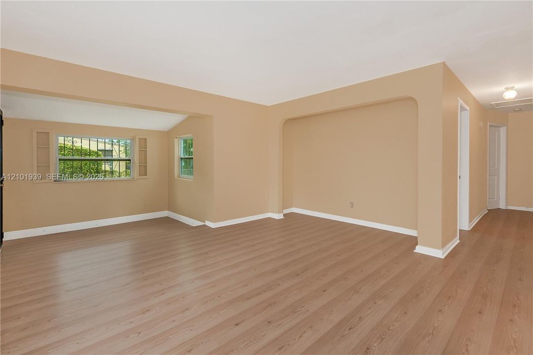 Interior space featuring wood-finish flooring, neutral wall paint, and an arched entryway