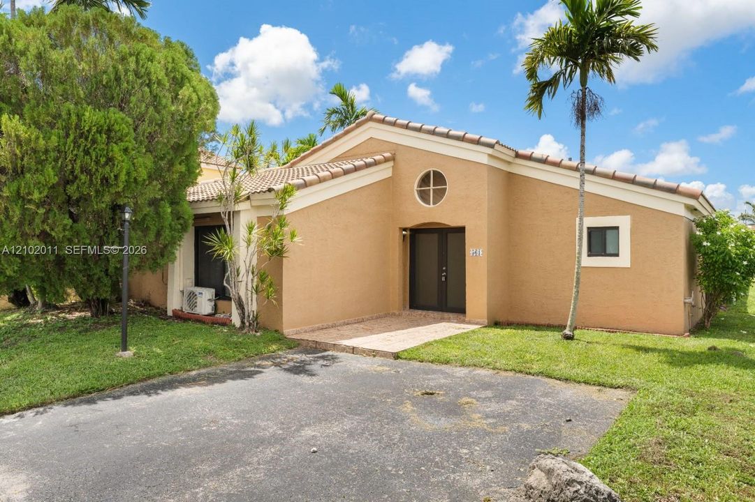 Stucco exterior with a tile roof, featuring a circular window and a paved entry