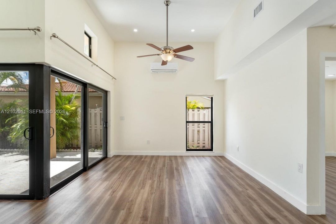 Vaulted ceilings, wood-finish flooring, ceiling fan, split-unit air conditioning, and sliding glass doors