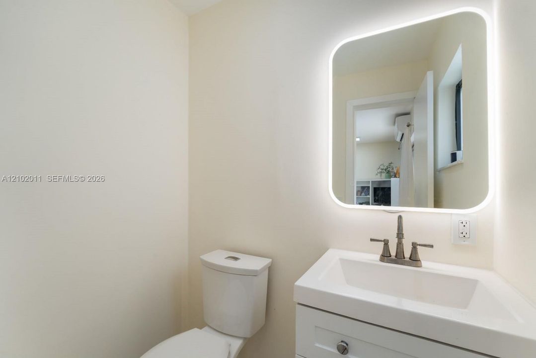 Illuminated mirror over a white vanity with an integrated sink and a two-handle faucet
