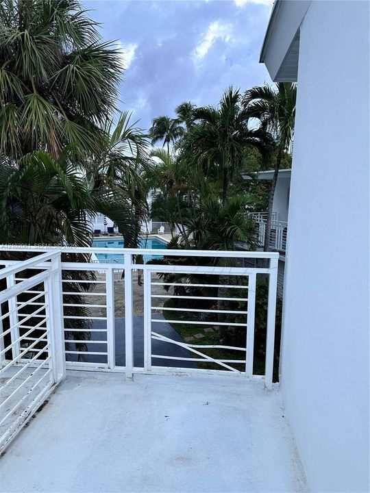 Balcony with white railing overlooking a pool area