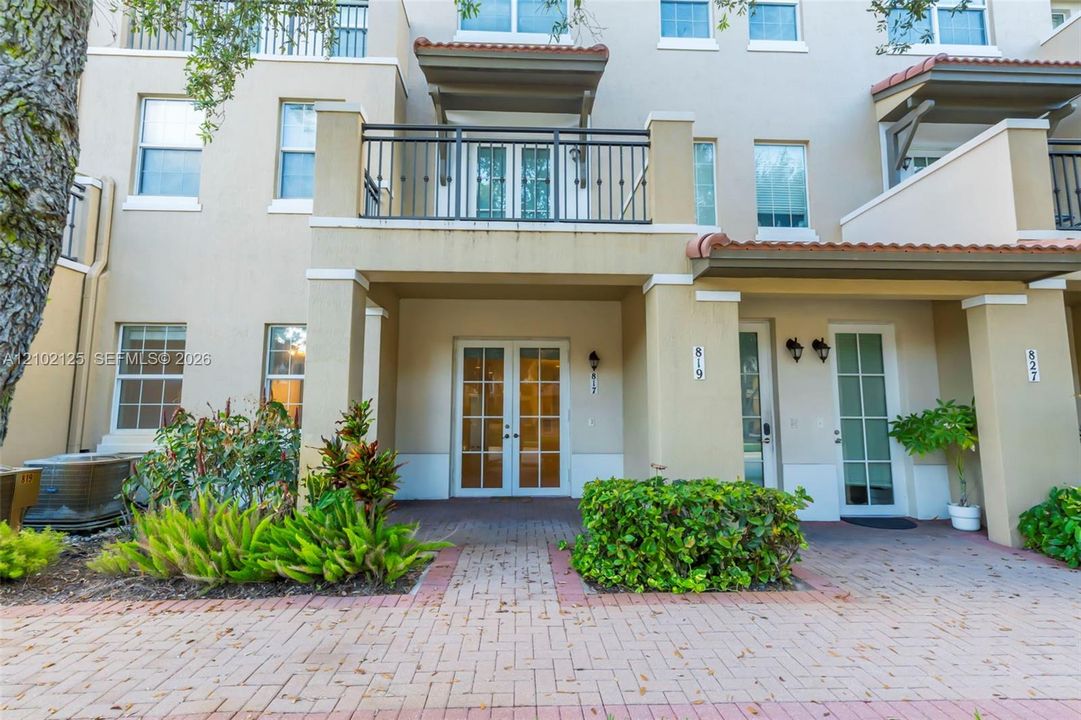 Exterior elevation featuring a stucco facade, dual French entry doors, and a brick-paver walkway