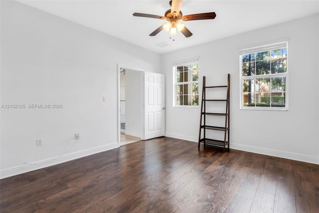 Wood-finish flooring, ceiling fan with integrated lighting, and multi-pane windows