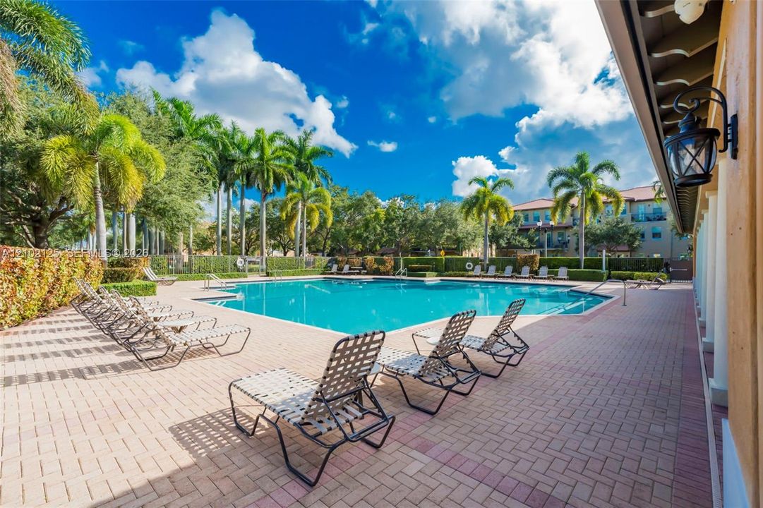 Swimming pool with paved surround, brick-patterned hardscaping, and mature perimeter landscaping