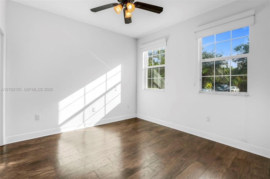 Wood-finish flooring, dual windows with grid muntins, and a ceiling-mounted light fixture