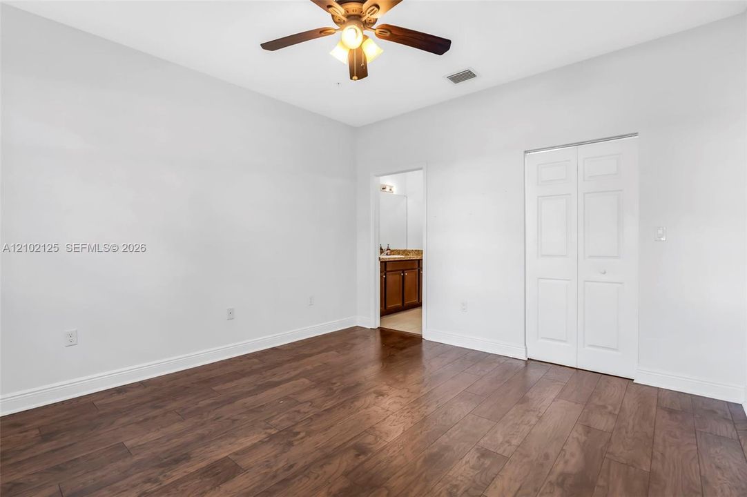 Room featuring wood-finish flooring, a ceiling fan with integrated lighting, and a double-door closet