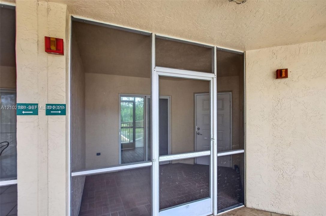 Screened-in entry porch featuring metal-frame door and windows, textured stucco walls, and tile flooring
