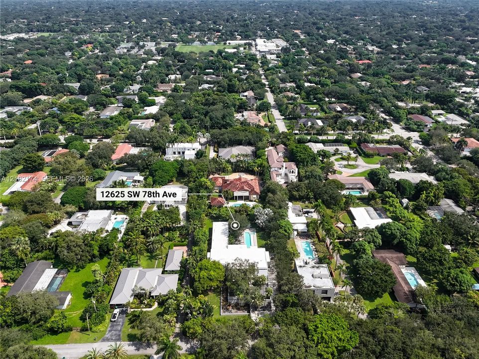 Aerial perspective featuring a residential lot with a rectangular swimming pool, expansive grounds, and mature tree canopy