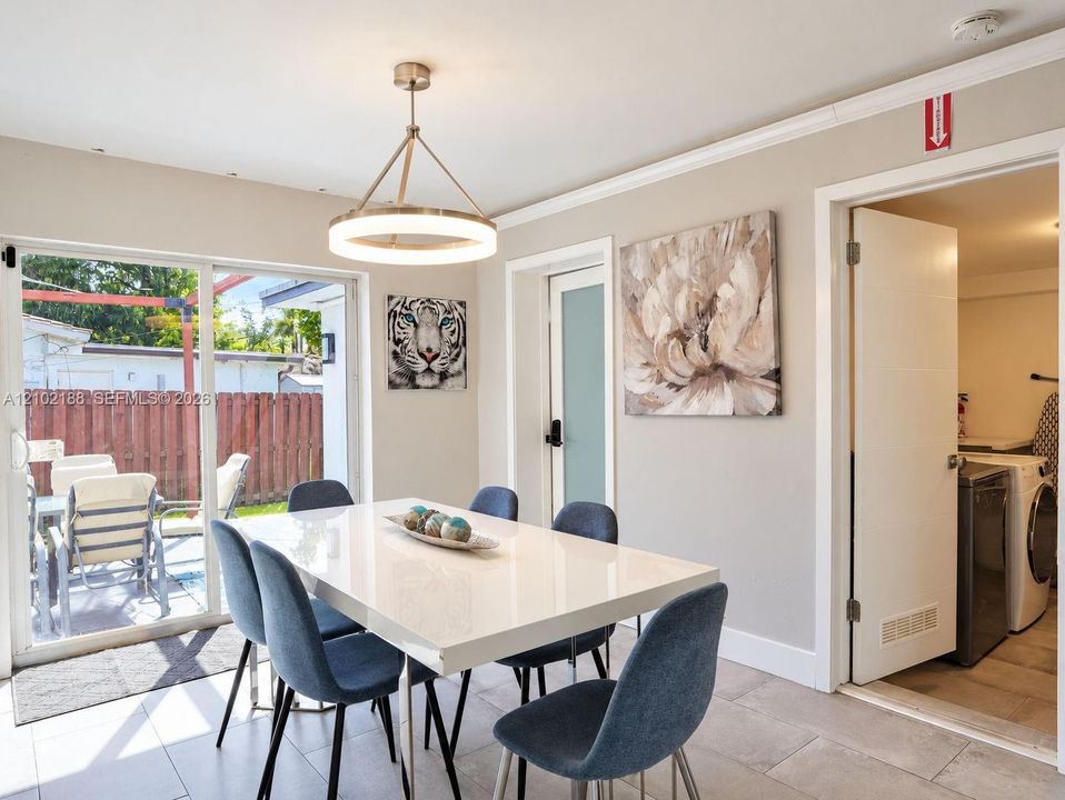 Sliding glass door, contemporary circular chandelier, crown molding, and neutral tile flooring