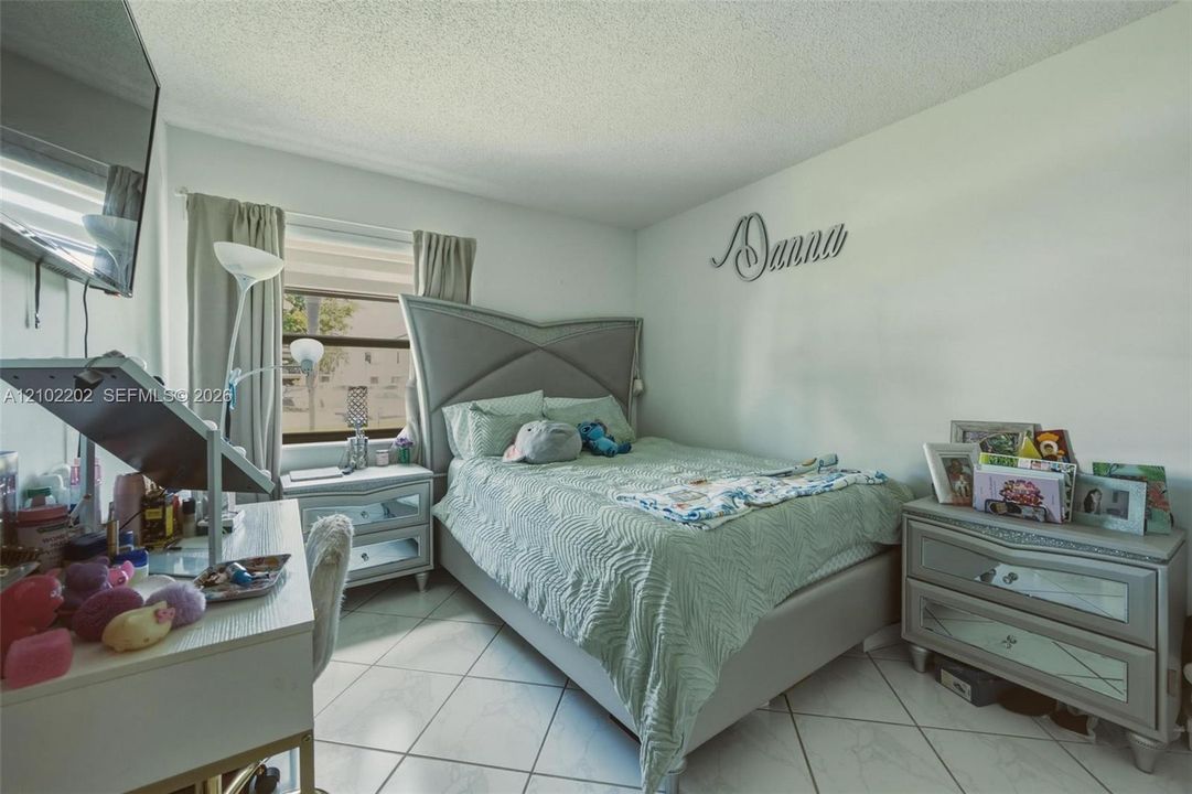 White tiled flooring, light-colored walls, and a window with blinds and drapes