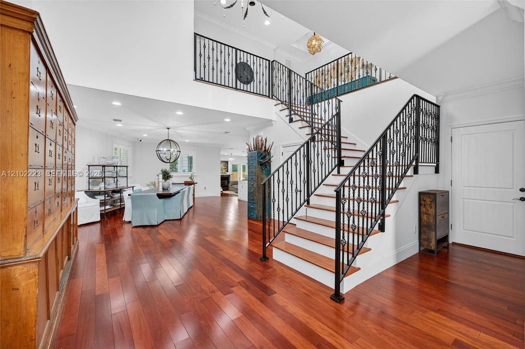 A striking architectural staircase with decorative rod, iron railings and warm wood, treads adds character and sophistication to the grand entry. Rich hardwood floors, soaring ceilings and an open view of the upper level. Create a wonderful sense of space while connecting the homes, beautiful designed living areas.