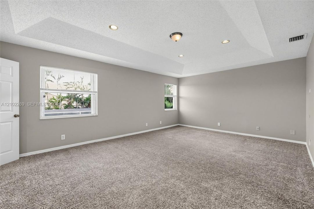 Tray ceiling with recessed lighting, neutral interior paint, wall-to-wall carpeting, and double-pane windows