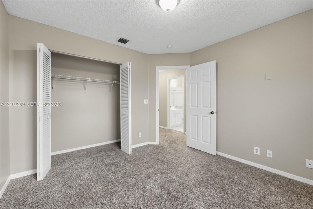 Neutral-toned interior space featuring neutral carpeting, a closet with louvered double doors, and a six-panel interior door