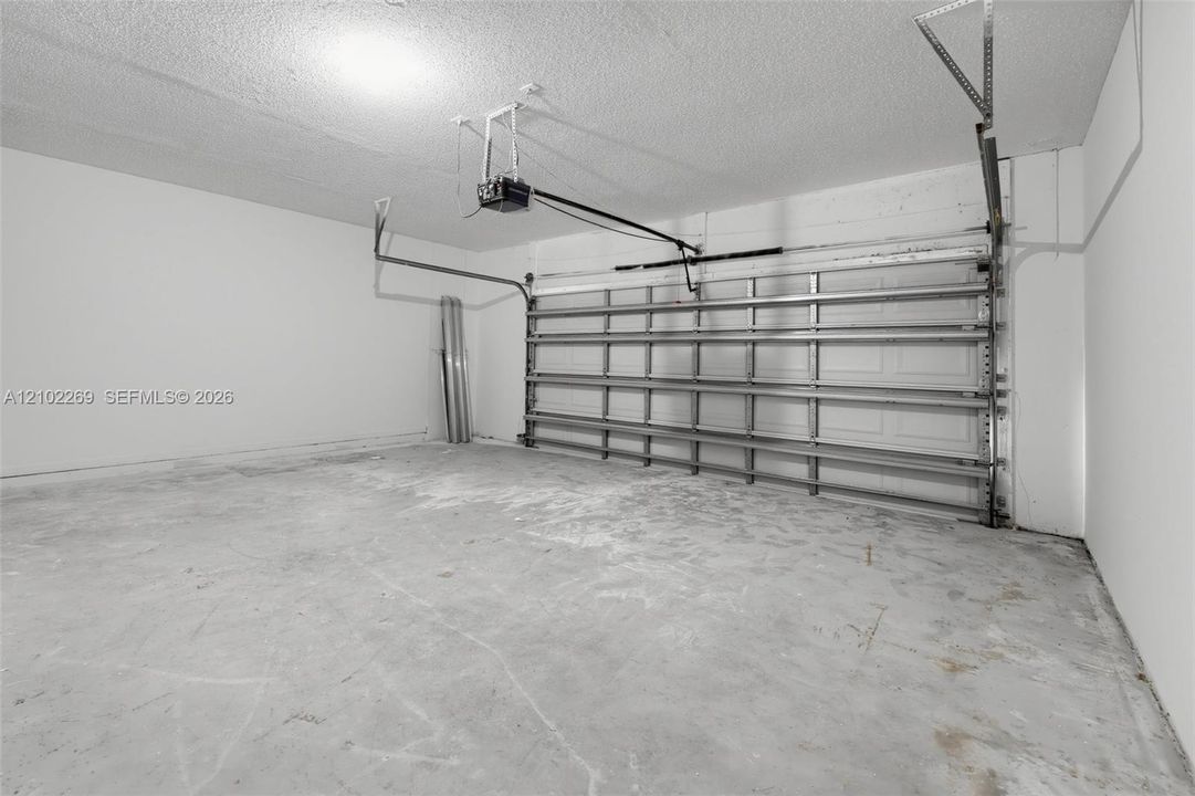 Enclosed garage featuring finished white walls, a concrete floor, and an automated overhead door system