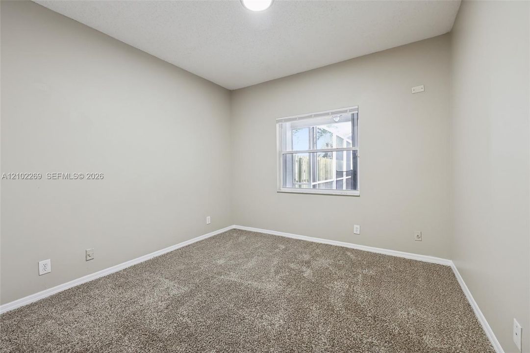Neutral-toned interior space featuring neutral wall-to-wall carpeting, a single-pane window with white horizontal blinds, and overhead lighting