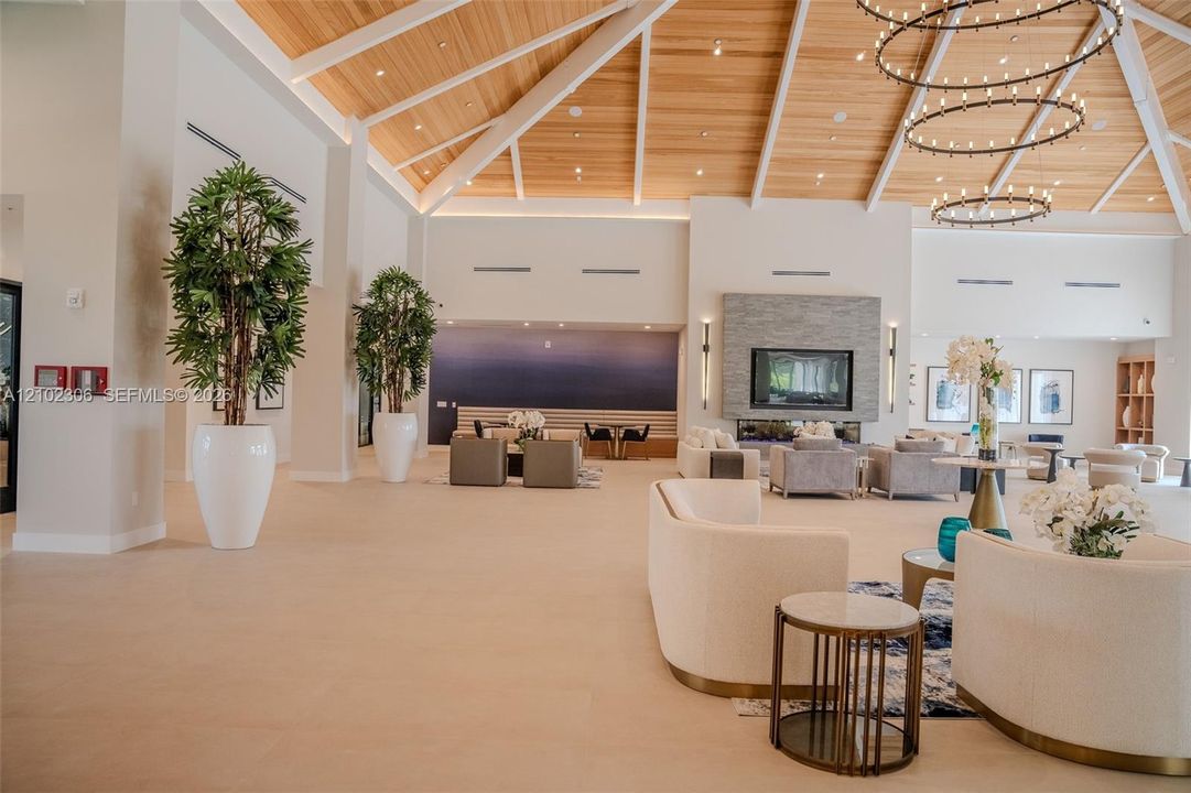 Vaulted ceiling with exposed wood-finish beams, stacked-stone fireplace, and multi-tier circular chandeliers