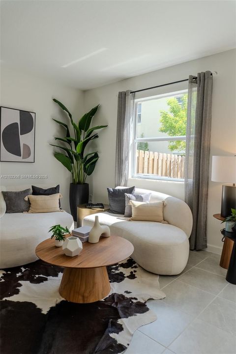 Neutral-toned interior featuring large-format tile flooring, crisp painted walls, and a substantial window with installed curtain rod hardware