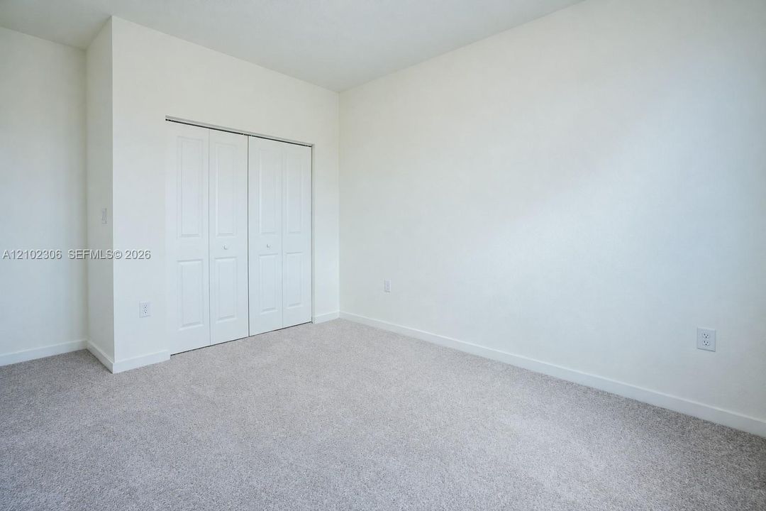 Neutral-toned carpeted flooring, white interior walls, and bi-fold closet doors with raised-panel detailing